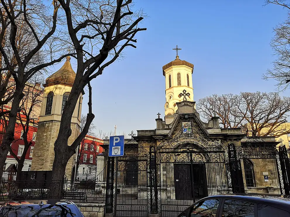 The Holy Trinity Church in Ruse, a low Orthodox church with an onion-domed bell tower and ornate wrought-iron gates, framed by bare trees