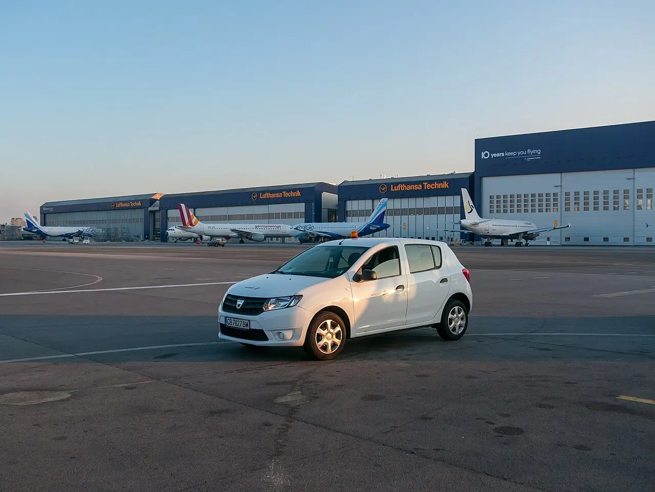 The exterior of Sofia Airport with parked cars and the terminal building under a bright sky
