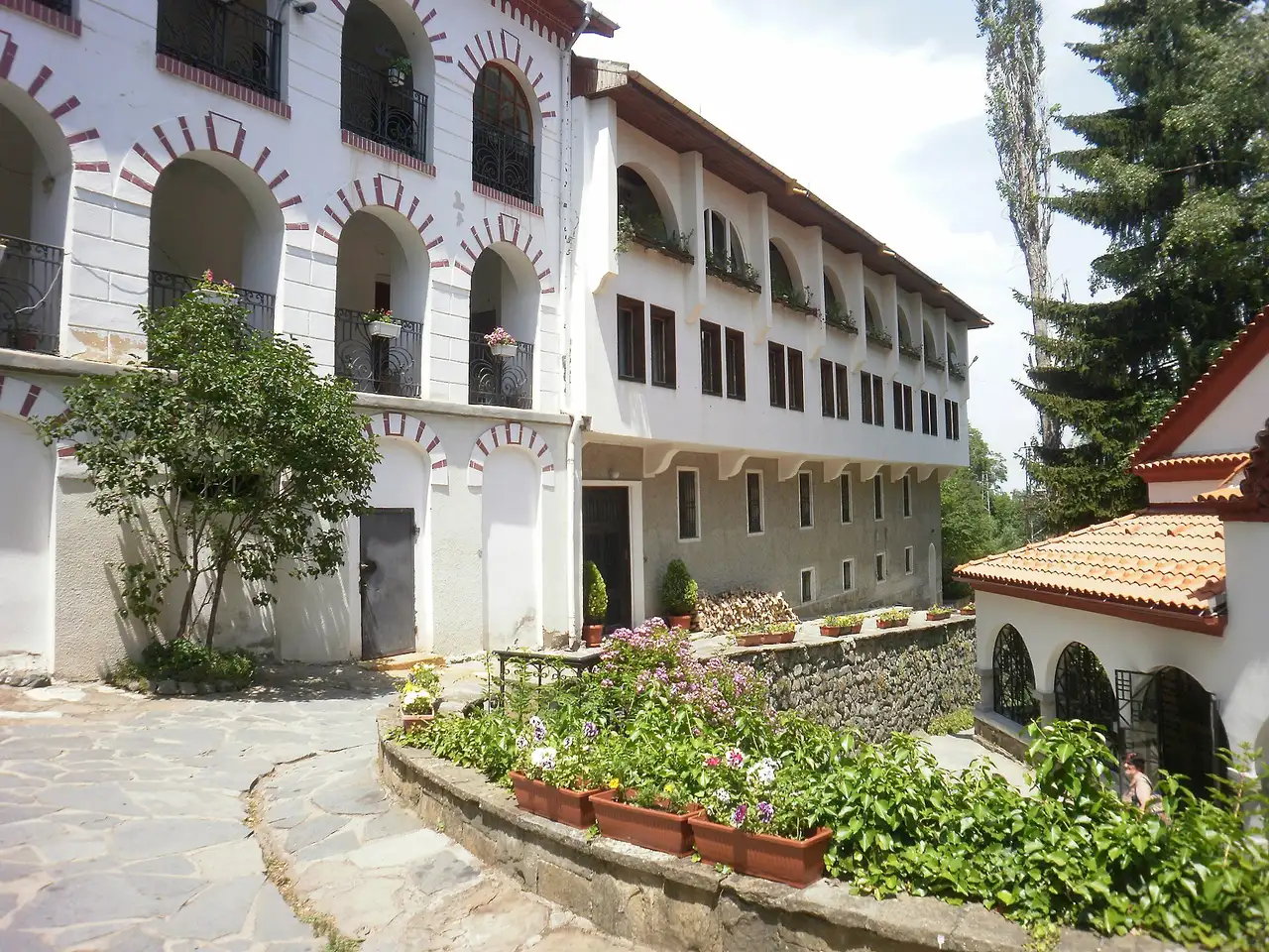 Whitewashed arcaded monastery buildings with red brick arches and flower boxes in the courtyard of Dragalevtsi Monastery below Vitosha