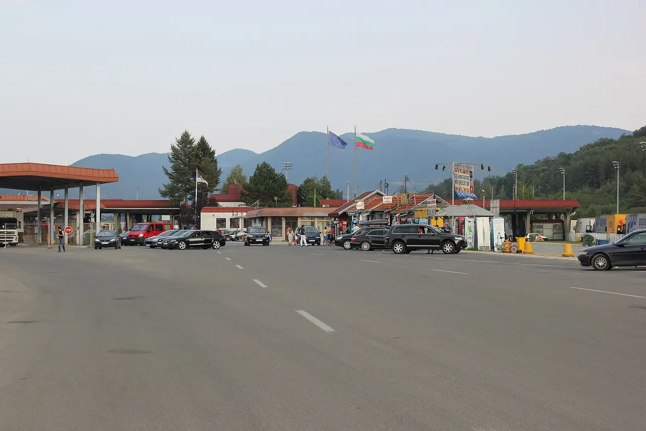 The Kalotina border crossing between Bulgaria and Serbia, control canopies and cars with the EU and Bulgarian flags flying and green hills behind