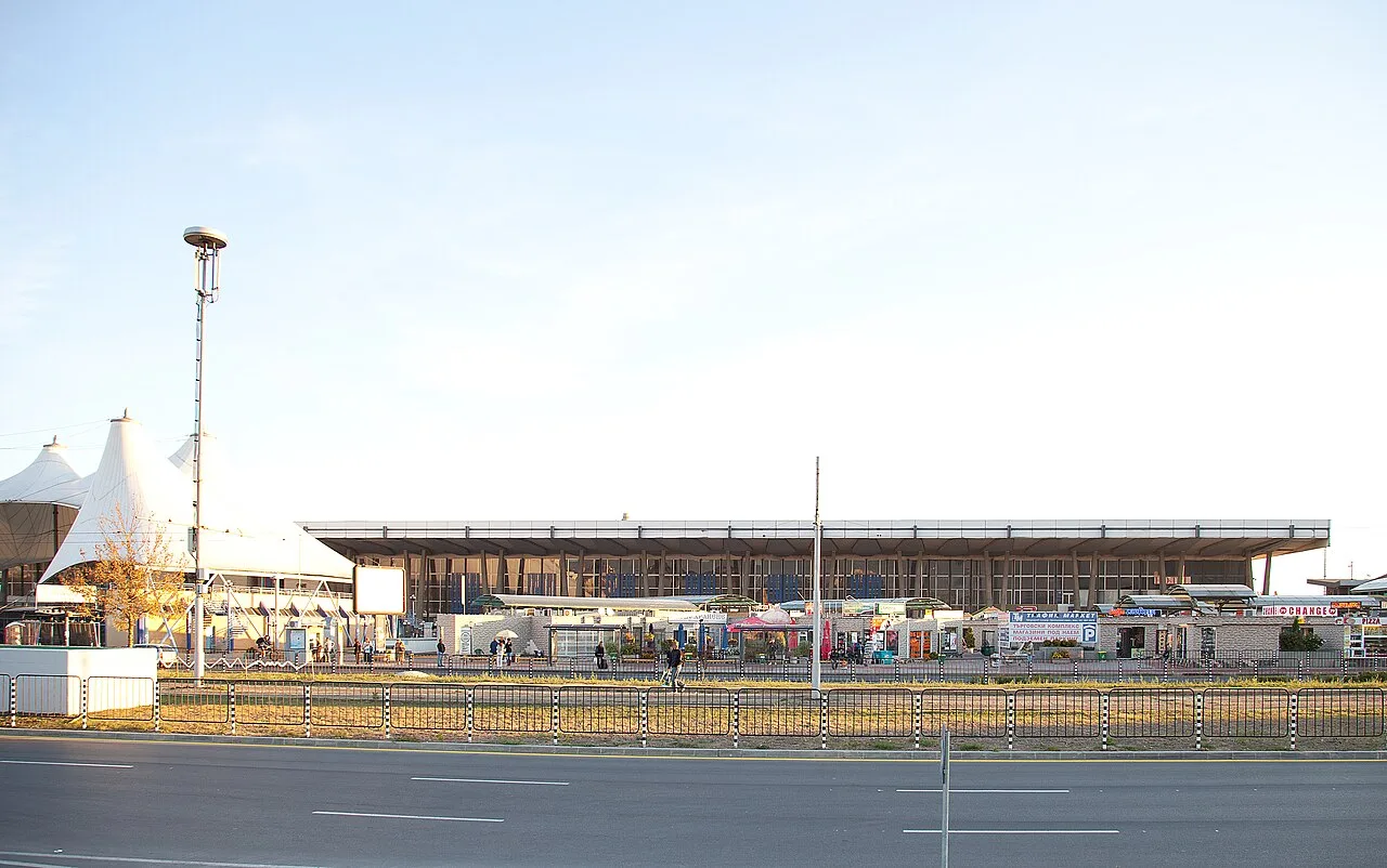 The low modern terminal building of Sofia Central Bus Station at dusk, with tent-like canopies, a currency exchange kiosk and the boulevard in front