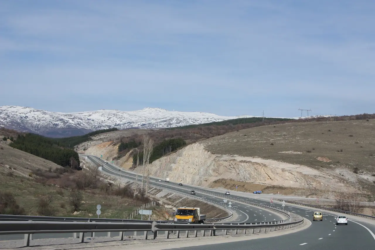 The A3 Struma motorway curving through hills south of Sofia with snow-covered mountains on the horizon