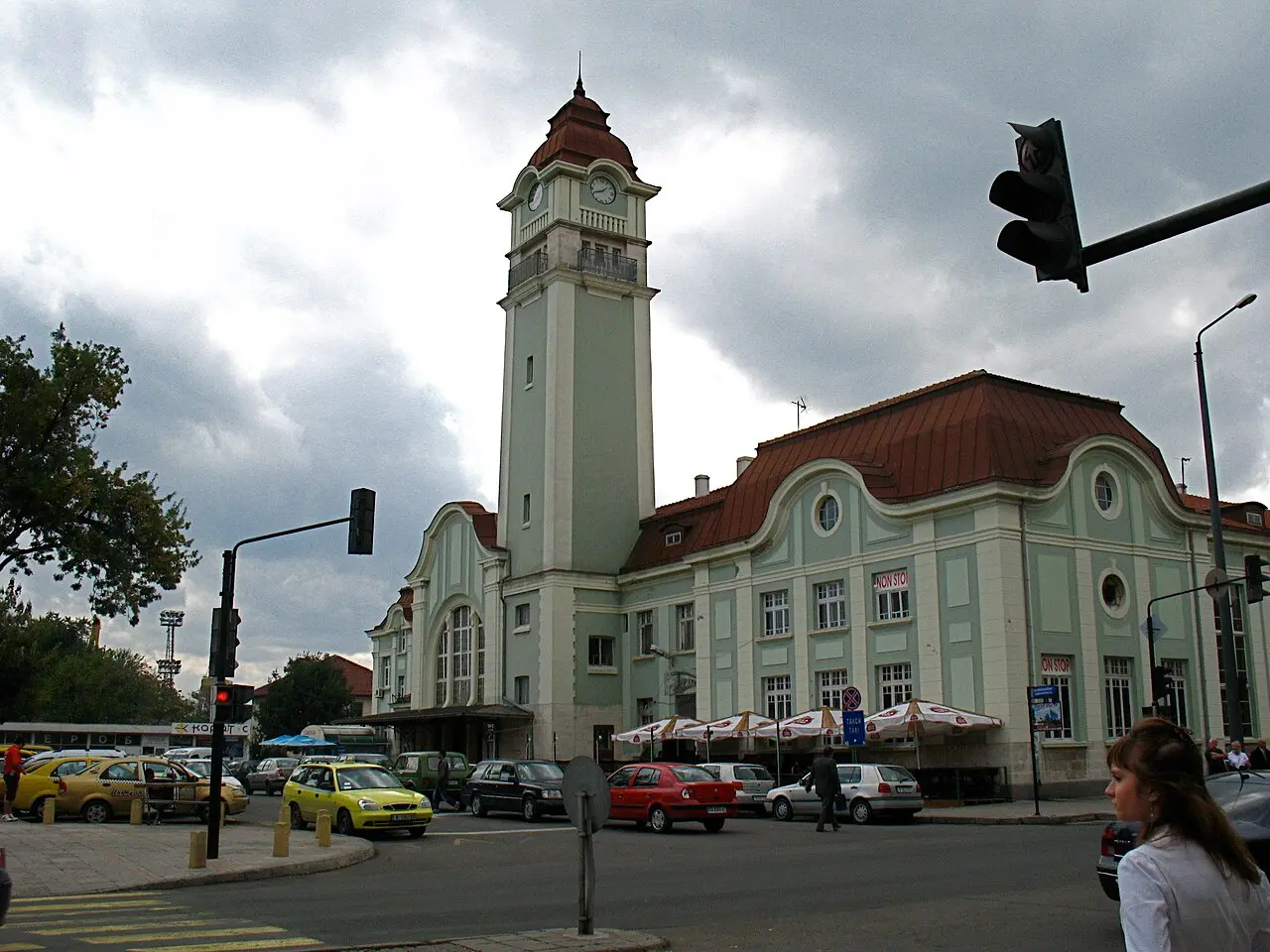The facade of Burgas Central Railway Station with palm trees and a square in front