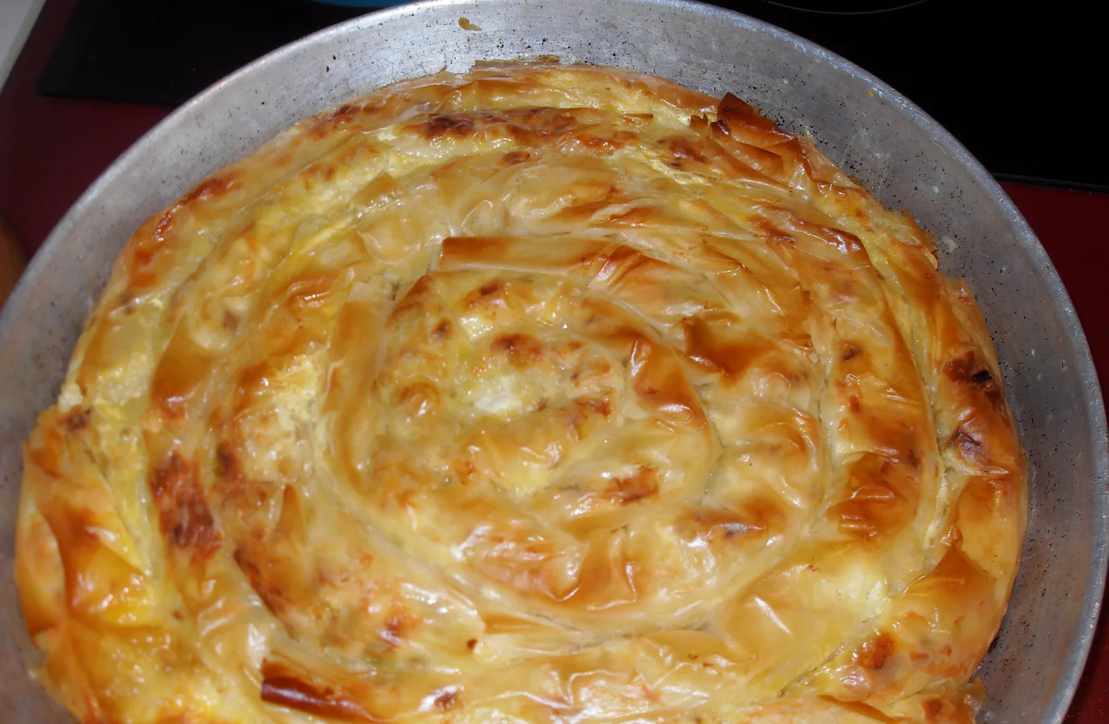 A whole spiral banitsa, a flaky Bulgarian cheese pastry, fresh out of the baking pan