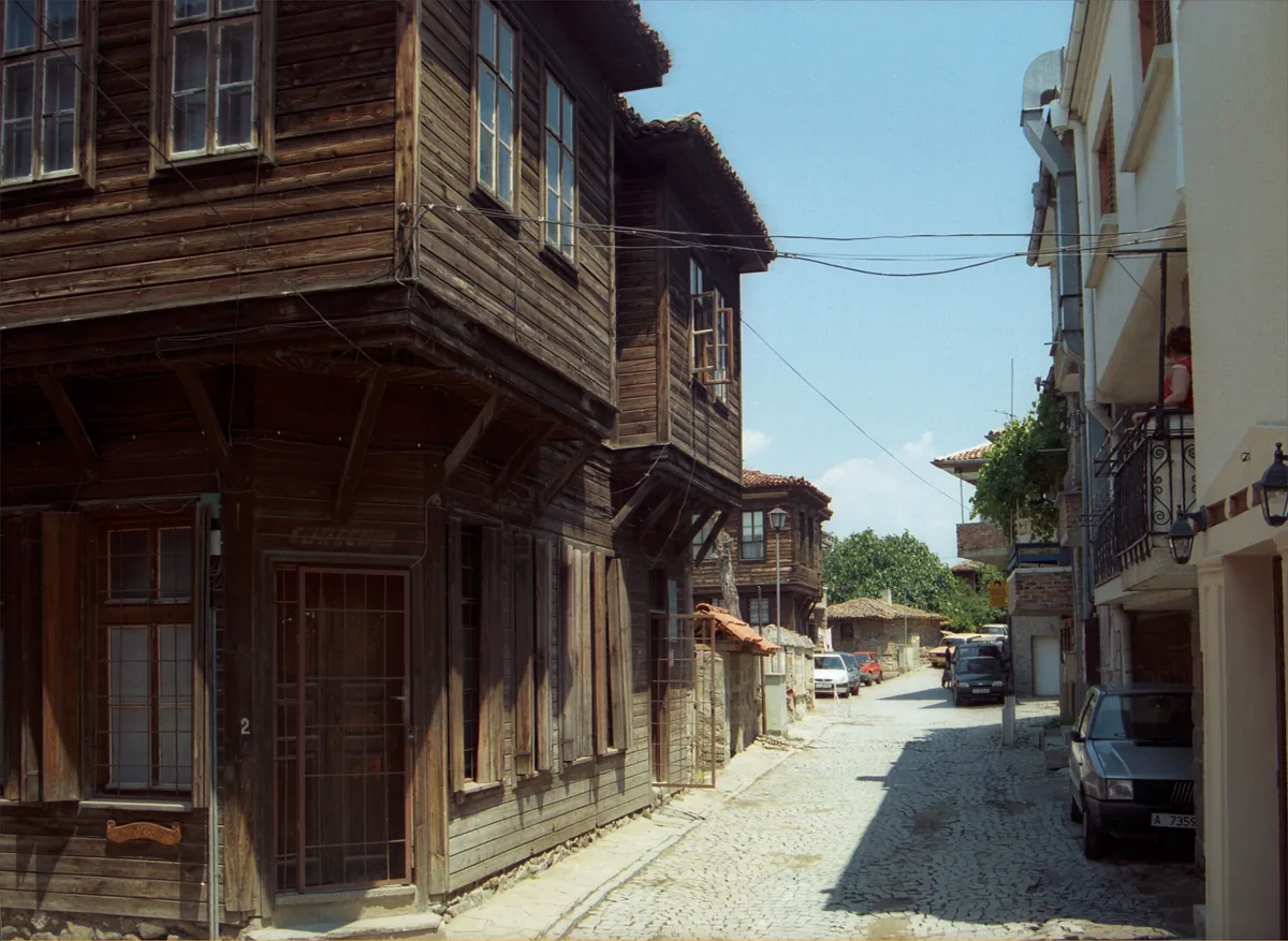 A narrow cobbled lane in Sozopol old town lined with stone-and-timber houses and greenery