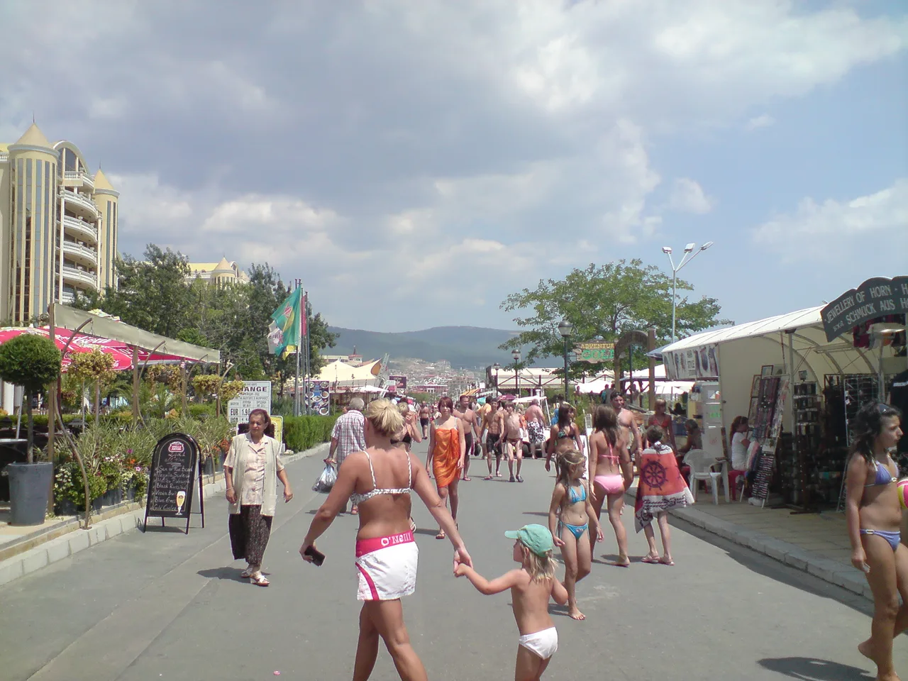 Crowds walking the pedestrian strip at Sunny Beach past bars and souvenir stalls on a summer day