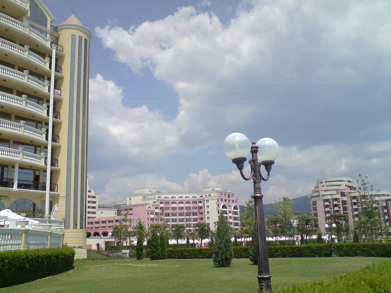Pastel-coloured resort hotels behind a lawn at Sunny Beach under a summer sky