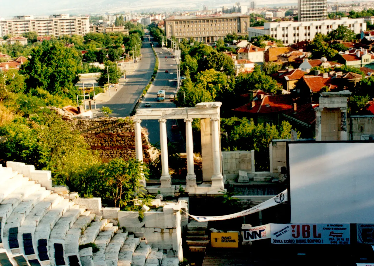 The restored ancient Roman theatre of Plovdiv, stone seating tiers and columns, with the city and hills behind