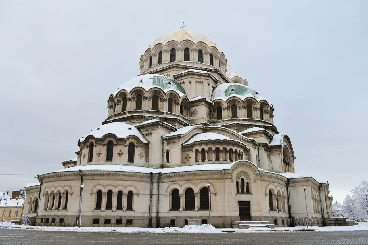 The gold and green domes of the Alexander Nevsky Cathedral in Sofia against a blue sky