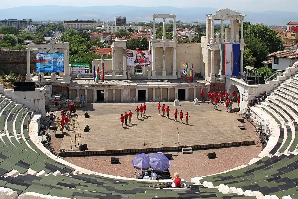 The marble seating tiers and columned stage of the Roman Theatre of Philippopolis in Plovdiv, mountains behind