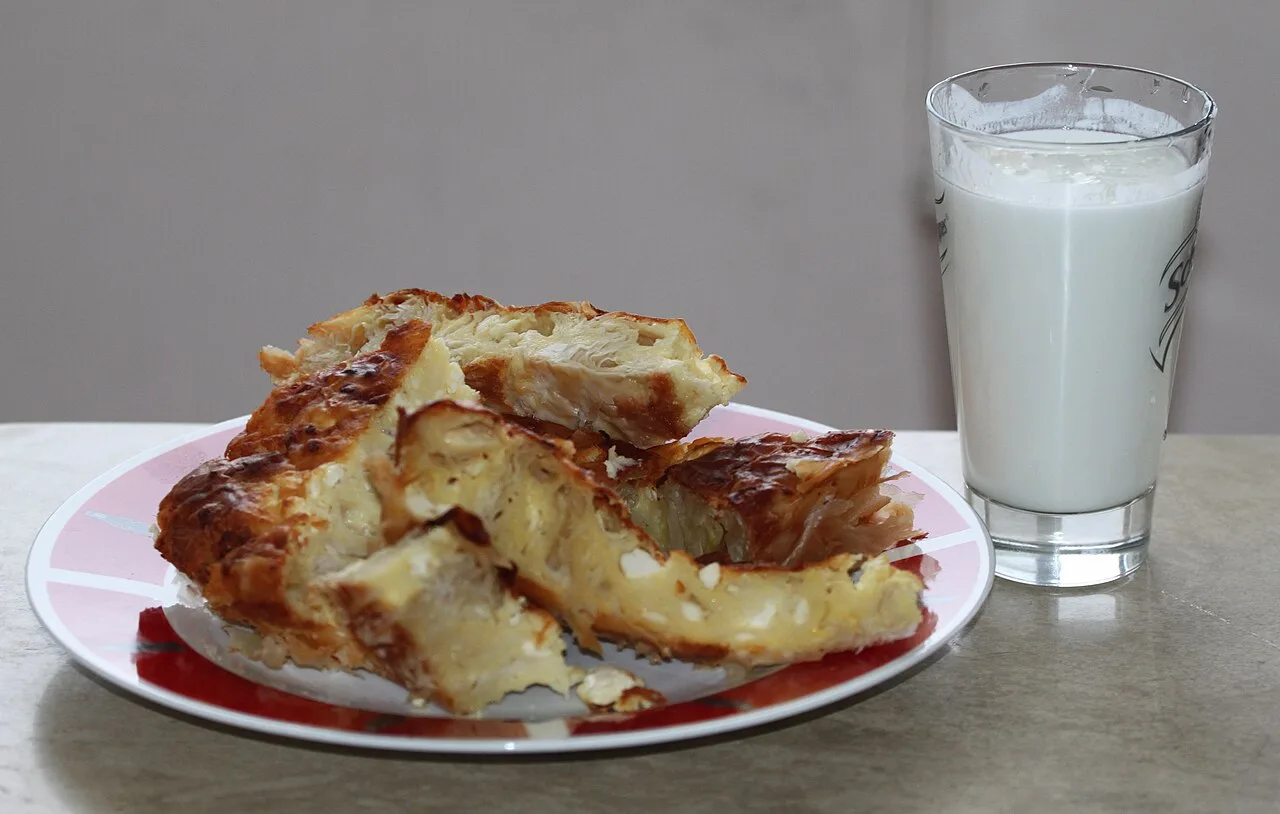 A plate of banitsa, Bulgarian filo cheese pastry, with a bowl of yogurt