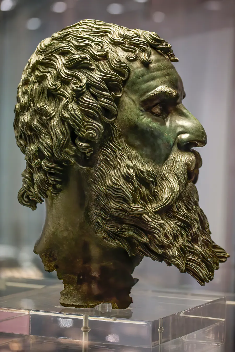 The almost life-size bronze portrait head of Seuthes III with curling hair and beard, displayed in a museum case