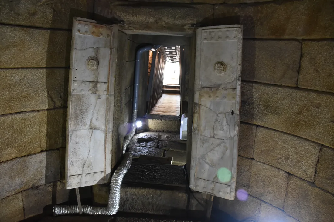 The open marble double door of the Golyama Kosmatka tomb with carved round medallions, looking down the lit corridor