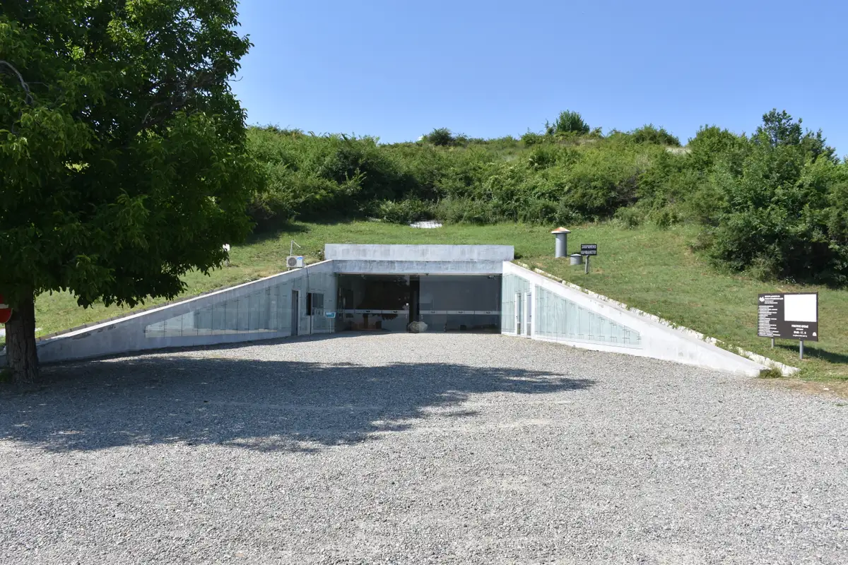 The modern concrete entrance cut into the grassy Golyama Kosmatka burial mound under a blue sky