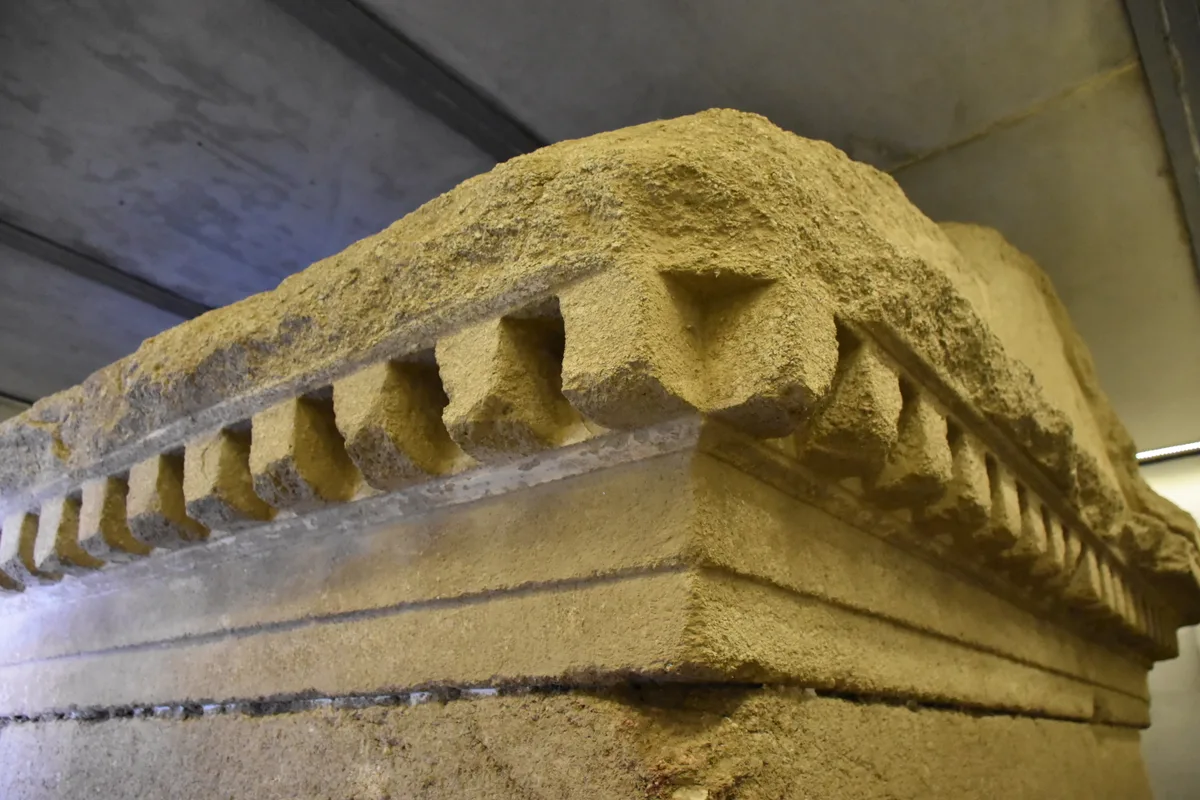 The Ostrusha burial chamber, a huge sandstone monolith carved with a temple-shaped roof, standing under a modern protective shelter