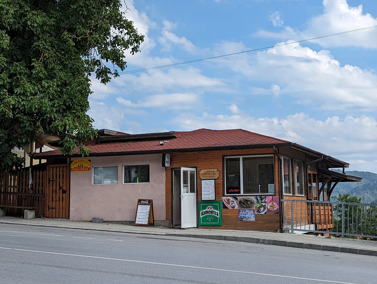 A small roadside Bulgarian restaurant and cafe in Smolyan with beer signs and a menu board out front