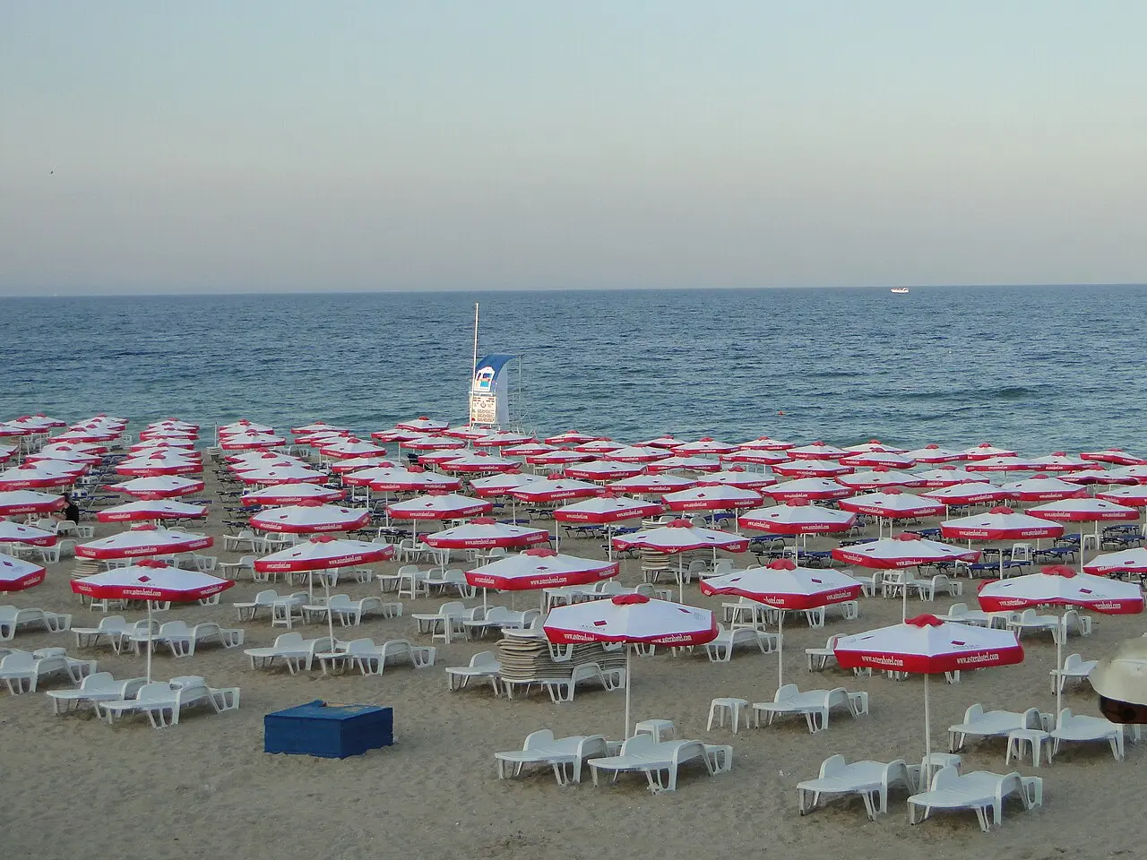 Rows of red and white sun umbrellas and loungers on the sandy beach at Golden Sands with the Black Sea behind