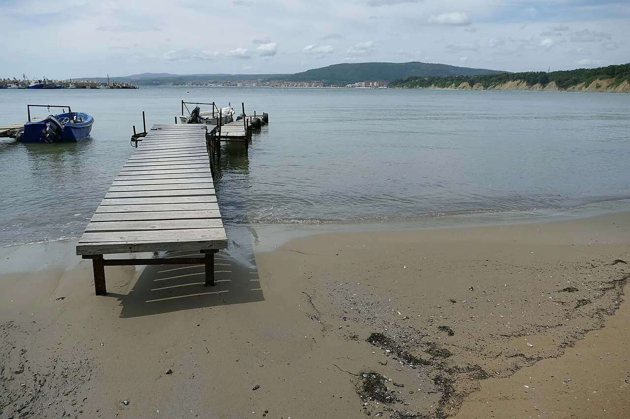 Beach by the harbour at Byala, piers under a grey sky