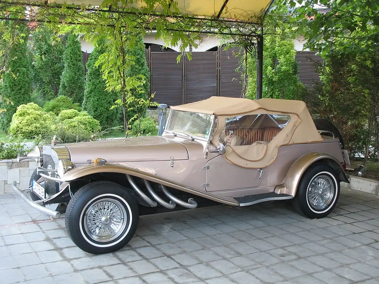 A vintage convertible parked under a canopy at a Sunny Beach hotel courtyard