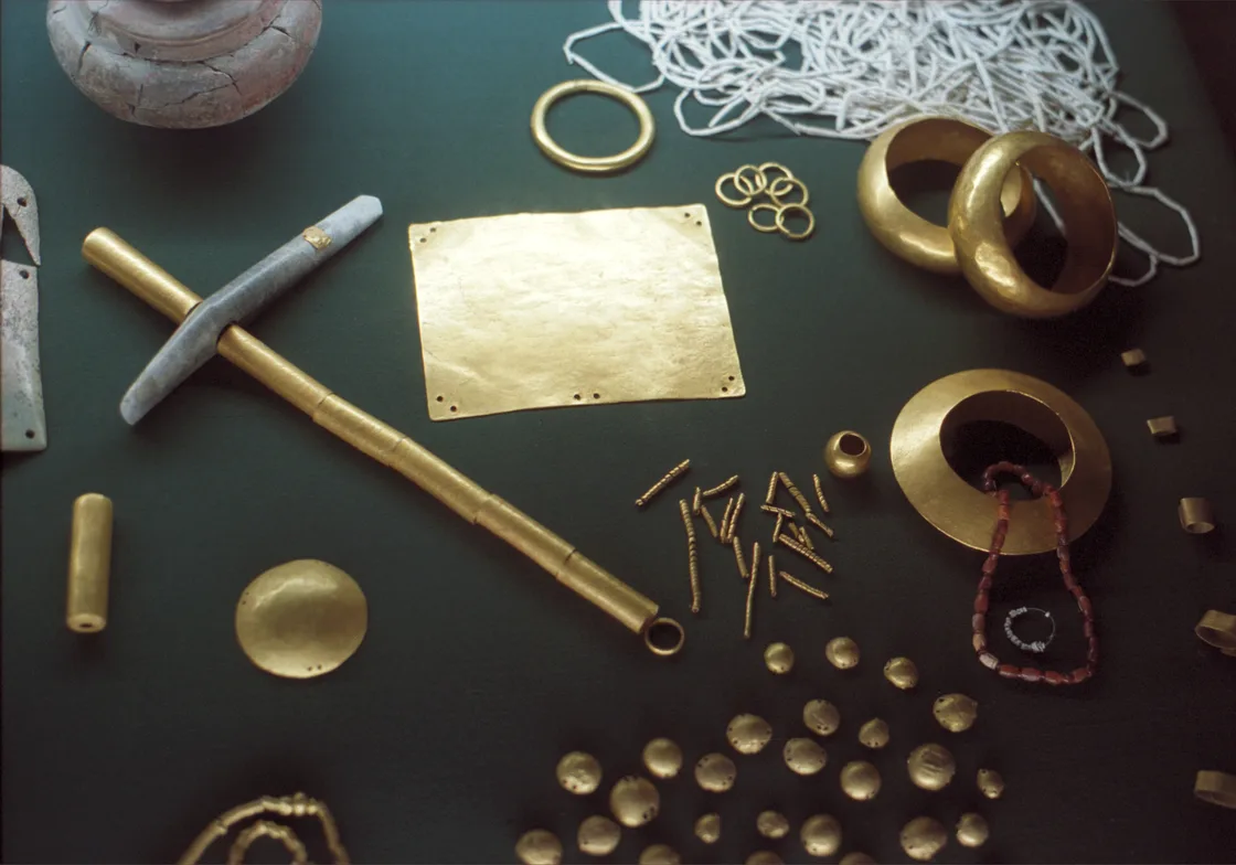 Gold objects from the Varna Necropolis on a dark background: bracelets, a gold sheet, a sceptre shaft, rings and small appliques