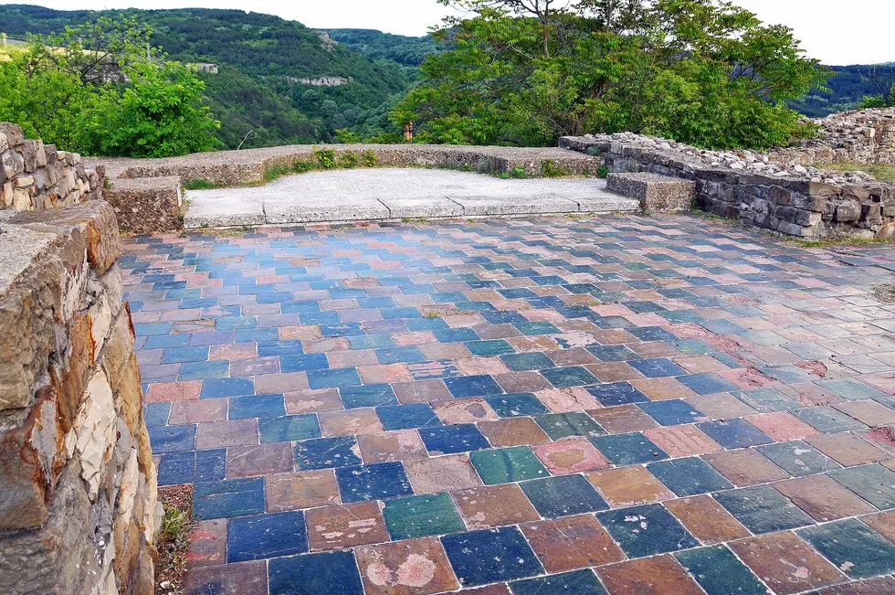 A floor of coloured medieval ceramic tiles on a terrace inside Tsarevets, with the wooded Yantra gorge behind