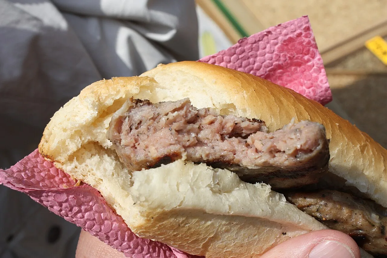 A grilled kebapche minced-meat roll in a bun, with a second one and a kyufte patty behind