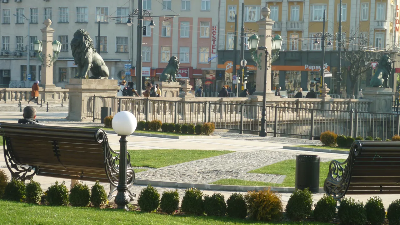 The Lions' Bridge in Sofia with its bronze lion statues, shops and a hostel sign in the buildings behind