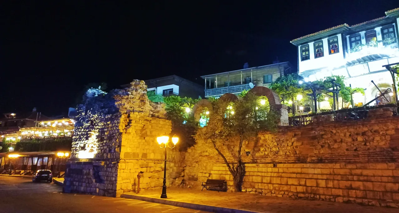 The old stone walls and lit-up seafront buildings of Nessebar old town at night