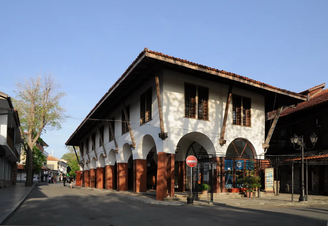 A street in Nessebar old town with a stone and timber Revival building and shops at ground level