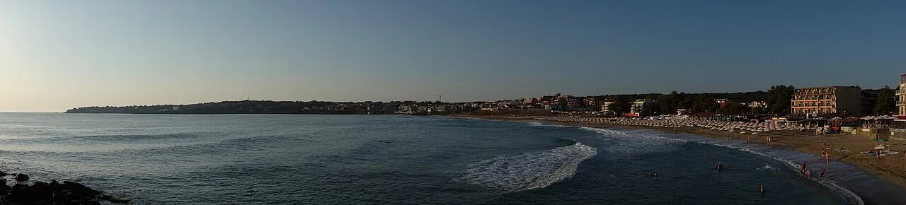 Panorama of Harmani beach in the new town of Sozopol, a wide curve of sand with sunbeds and the town rising behind
