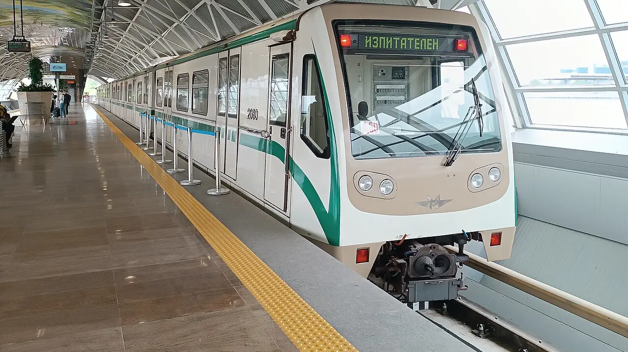 The underground metro platform at Sofia Airport station on the M4 line, with a train waiting and passengers on the platform
