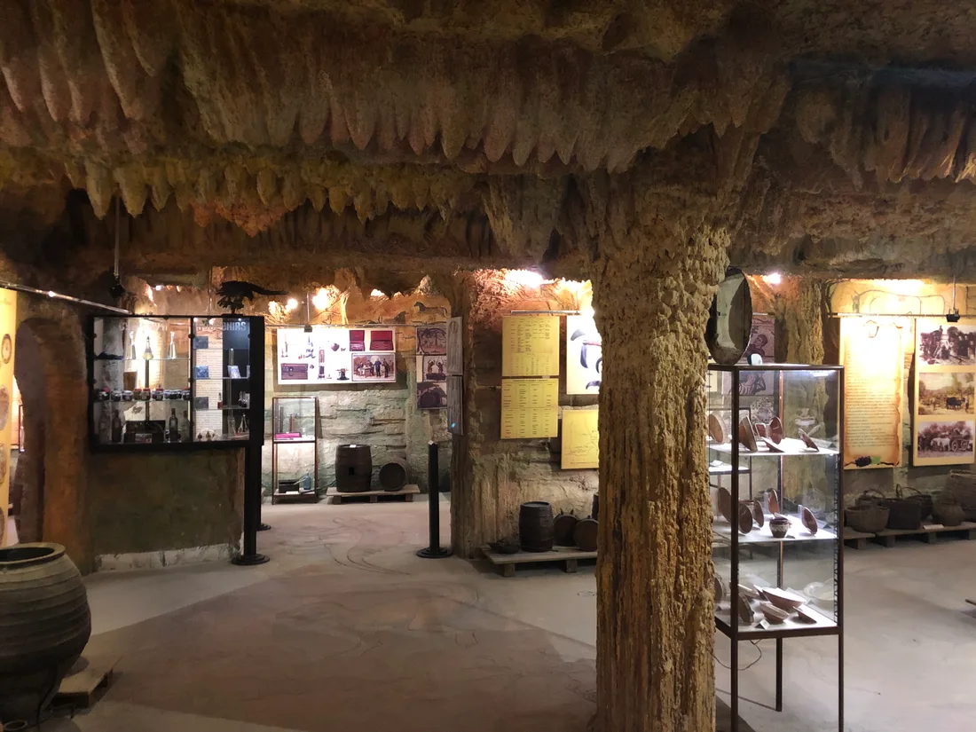 The interior of the Melnik wine museum, a rock-cut hall with stone pillars, display cases and old wine-making vessels