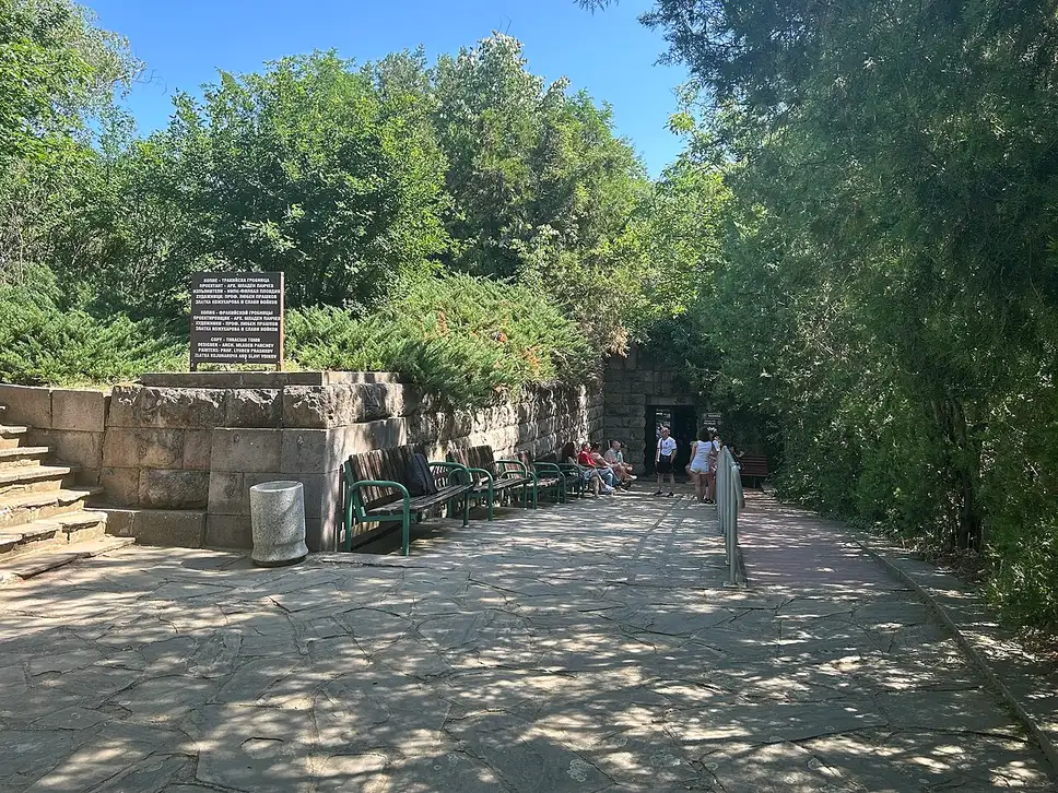 The tree-shaded entrance to the Thracian Tomb of Kazanlak, with visitors on the path