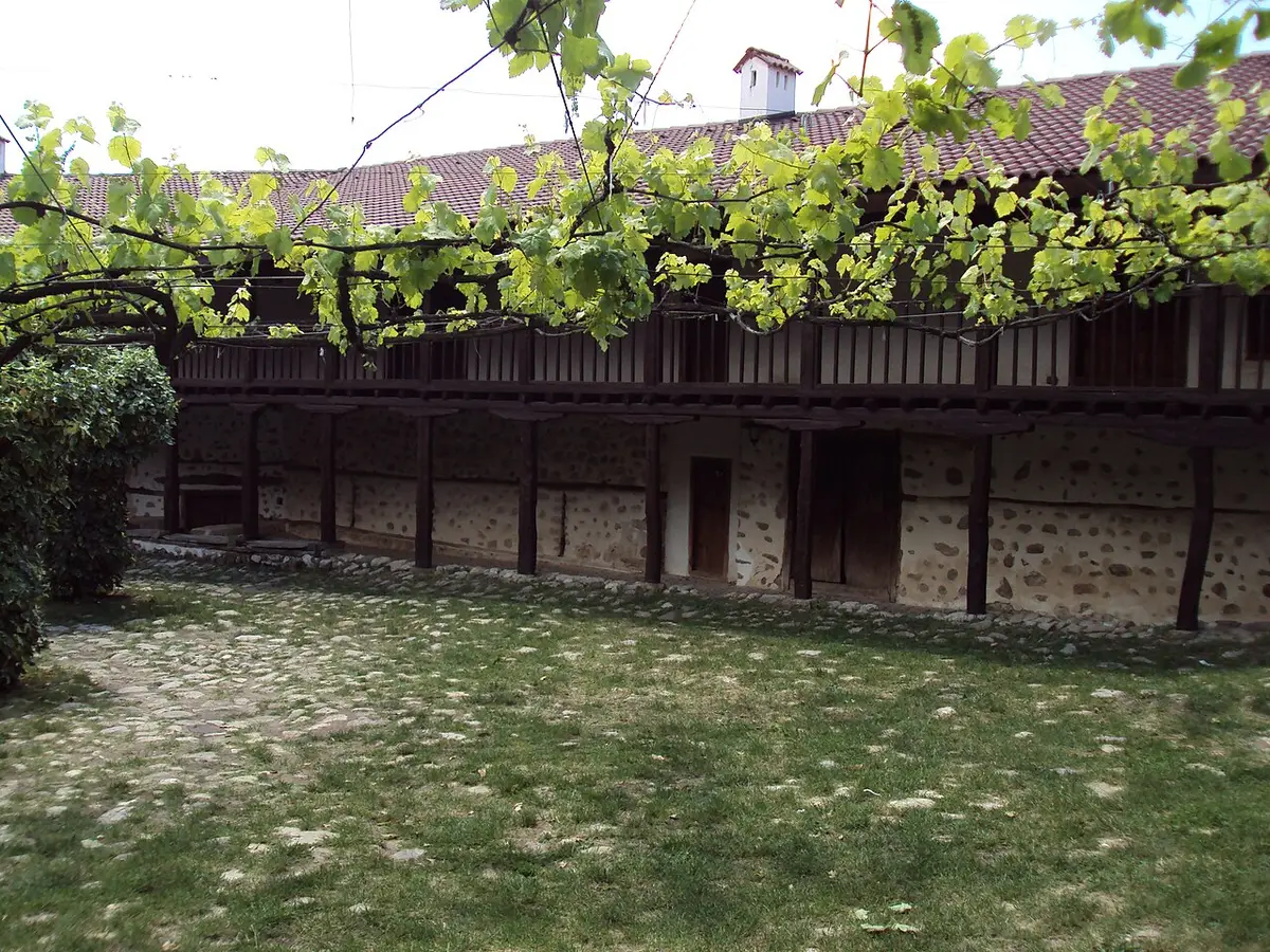 The wooden-galleried courtyard of Rozhen Monastery with a grapevine pergola over the stone yard